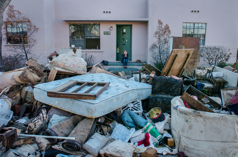 A New Orleans resident sits on the steps of her home as all of the contents lie in the street.  The home was flooded by Hurricane Katrina and the subsequent levee failure. www.kathyandersonphotography.com